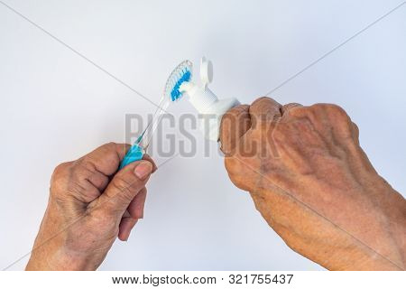 Senior Woman's Hands Squeezing Toothpaste On Brush Against Isolated On White Background