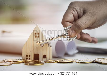 Ownership Hold Key Against House With Miniature Home For Protect And Insurance Document With White B