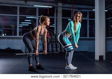 Young Sports Girl Does Deadlift With A Barbell In The Gym Under The Supervision Of A Trainer. Female