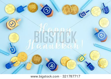 Blue Background With Dreidels, Menora Candles And Chocolate Coins With Happy Hanukkah Wording. Hanuk