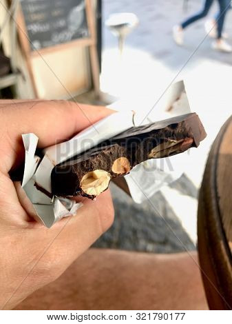 Holding Biten Bitter Almond Chocolate Bar. Organic Sweet Snacks At Cafe Shop.