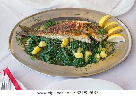 Balkan Cuisine. Grilled Fish (sea Bream) With Green Leafy Vegetables And Lemon Slices