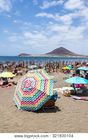 El Medano, Spain - July 7 2019: People Swimming And Sunbathing On Playa El Medano Beach On July 7, 2