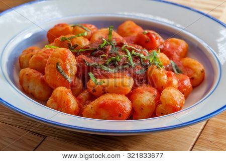 Italian Gnocchi In Red Marinara Tomato Sauce With Basil On Wooden Kitchen Table