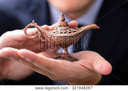 Businessman With Aladdin Ali Baba Lamp In His Hands Seeking Genie Help