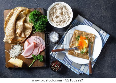 Breton Crepe,  Buckwheat Galettes Bretonnes With Sunny Side Up Egg, Cheese, Ham On A White Plate On 