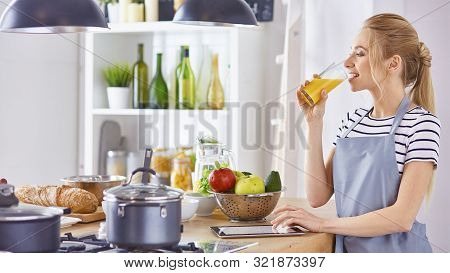 The Girl At The Table In The Kitchen With A Glass Of Orange Jui