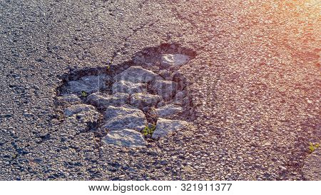 Pothole On Asphalt Closeup With Blue And Gray Stones. Background Texture