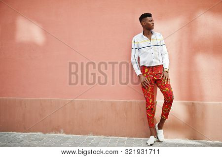 Portrait Of Handsome Stylish African American Model Man In Red Throusers And White Shirt Against Pin