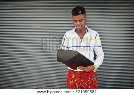 Portrait Of Handsome Stylish African American Model Man In Red Throusers And White Shirt With Laptop
