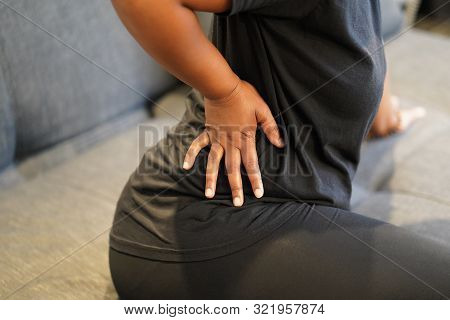 Close-up View Hand Of African Woman With Pain In Kidneys At Home. Young African Woman With Back Ache