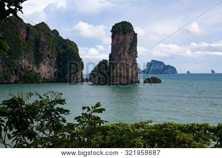Picturesque beach with a view on the huge rock formation, sea view of Andaman sea and golden sand, iconic sight in Krabi province, Thailand.