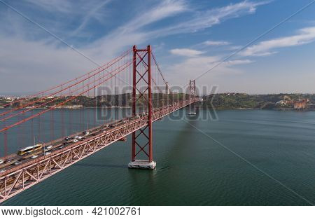 Long Red Multideck Suspension Bridge Connecting Lisbon To Almada Over Wide River From Drone. Heavy T