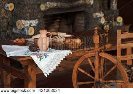 Variety Of Food Ingredients For Bread Baking Along With Retro Spinning Wheel Placed On Table In Coun