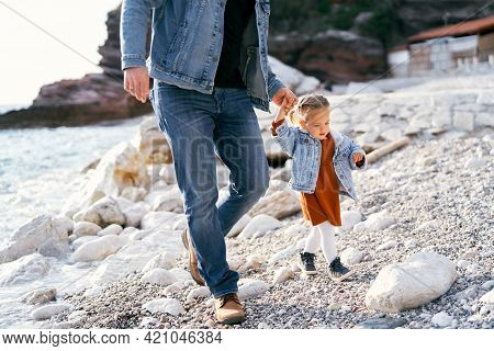 Dad Leads A Little Girl By The Hand Over The Stones On A Pebble Beach Near The Town Of Rafailovici, 