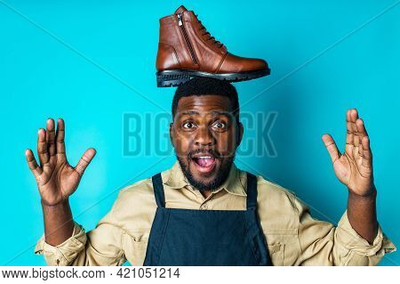 Latin Hispanic Man In Black Apron Showing Brown Leather Shoes In Blue Studio Background