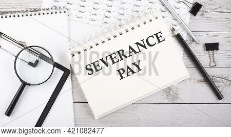 Notepad With Text Severance Pay With A Pen,office Tools And Graphs On Desktop.