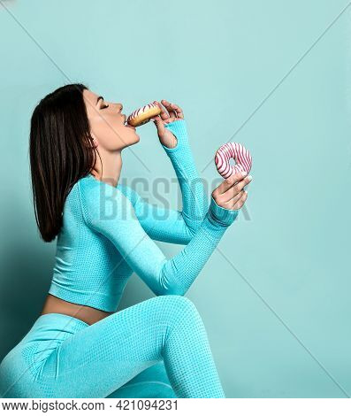 Sporty Slim Woman In Turquoise Sportswear Loses Willpower And Bites A Sweet Donut. Fitness Woman On 