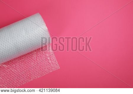 Bubble Wrap Roll On Pink Background, Top View. Space For Text
