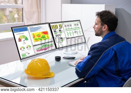 Industrial Engineer Sitting At Workplace Behind Computer Monitor