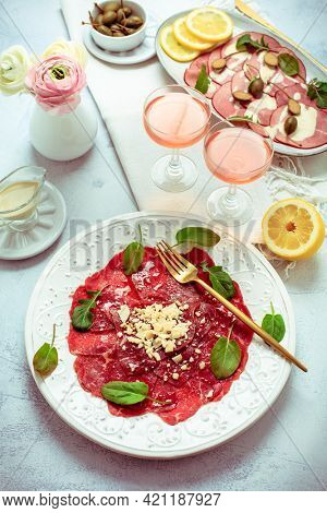 Appetizers - Vitello tonnato and beef Carpaccio with two glasses of rose wine.