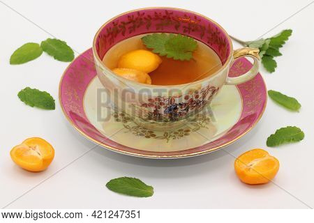 A Beautiful Vintage Porcelain Tea Cup With A Melissa Leaf And Calamansi Slices. Mint Leaves And Cala