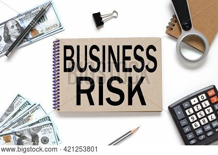 Business Risk. Business Concept. Notebook On White Workspace. Near The Notepad Dollar Bills And A Ca