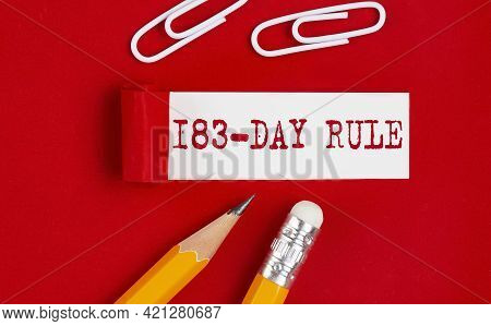 183 Day Rule Message Written Under Torn Red Paper With Pencils And Clips,
