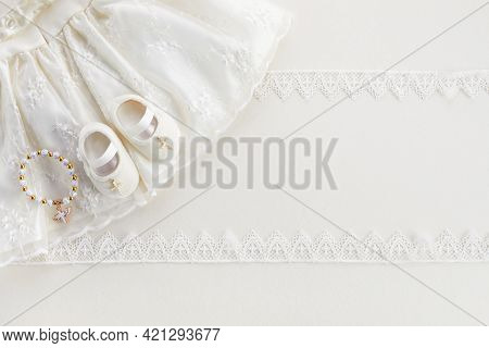 Christening Background With Baptism Baby Dress, Shoes, And Cross On Pastel Background