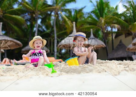 Due sorelle carina sono seduti e giocare sulla spiaggia esotica
