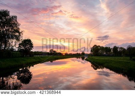 Beautiful Setting Sun With Colored Clouds And The Reflections In The Water Of The River Called 