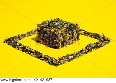 Japanese Green Tea Genmaicha. Tea Leaves With Fried Brown Rice In The Shape Of A Cube On A Bright Ye