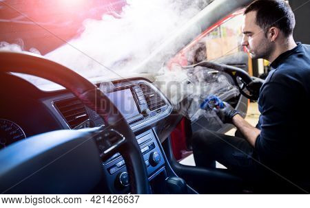 Car Service Worker Cleans Interiror With Steam Cleaner