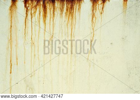 Dark Orange Streaks On A Pale Yellow Plaster Wall. Orange And Brown Streaks Of Rust Stain A Light Ye