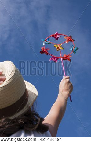 Young Woman Holding Colorful Bright Rainbow Toy Pinwheel Against Blue Sky