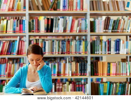 Portrét chytrý student s otevřenou knihou čtení v knihovně školy