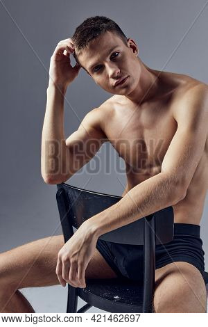 A Sporty Man With A Muscular Body Sits On A Chair With His Elbows On The Back