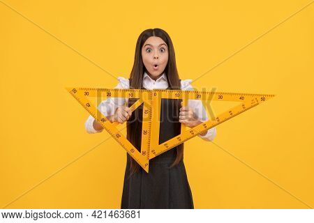 Amazed Teen Girl Hold Math Triangle Ruler In School On Yellow Background, Education