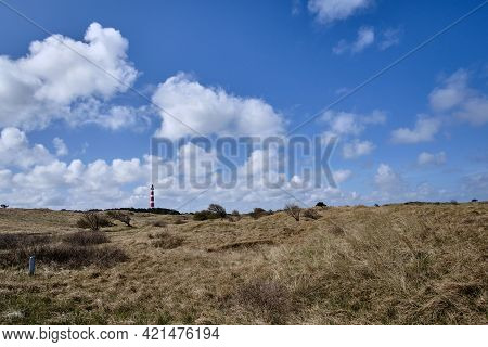 Dune Valley With Beach Grass And A Blue Sky And In The Background A Classic, Historic Old Red And Wh