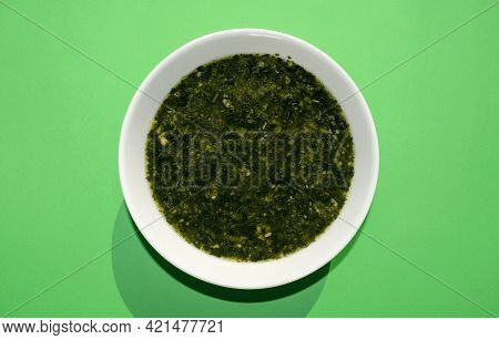 Famous Traditional Arabic Cuisine. Molokhia Soup In A White Bowl On A Green Background. Flat Lay, To