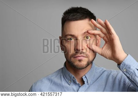 Man Checking His Health Condition On Grey Background, Space For Text. Yellow Eyes As Symptom Of Prob