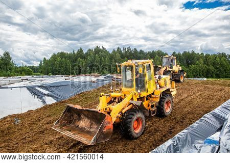 Agricultural Machinery For Harvesting Silage. A Bulldozer Compact The Cut Grass In A Silage Trench O