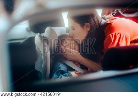 Mother Kissing Her Child Sleeping In Car Chair