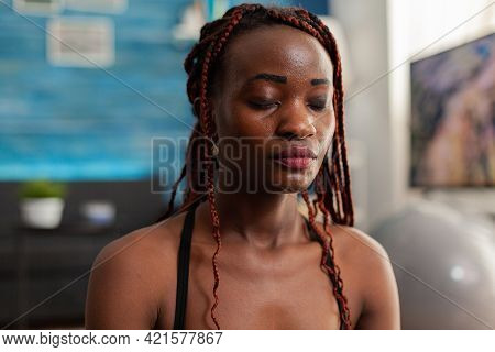 Black Woman Training Body And Mind Meditating In Lotus Pose Keeping Eyes Closed, Sitting On Yoga Mat
