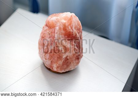 An Orange Salt Lamp Stands On A White Bedside Table