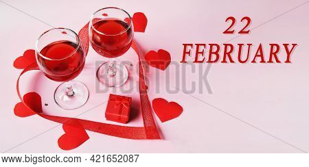 Calendar Date On Light Background With Two Glasses Of Red Wine, Red Gift Box And Red Hearts With Cop