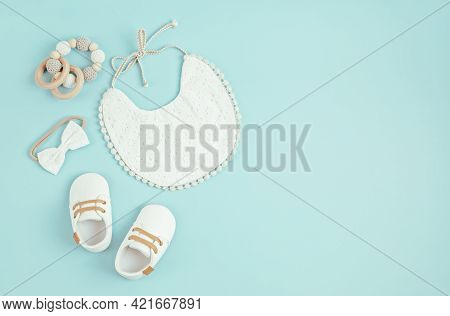 Baby Shoes, Bib And Teether On Blue Background. Organic Newborn Accessories