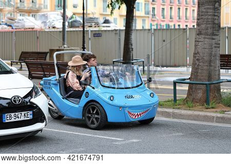 Nice, France - May 21, 2019: Nicecar Three-wheel Vehicle, Funny Small Blue Sharing Car, Young Couple
