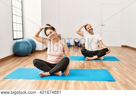 Mature hispanic couple doing excersice and stretching at yoga room. Two adult people doing pilates and flexibility workout