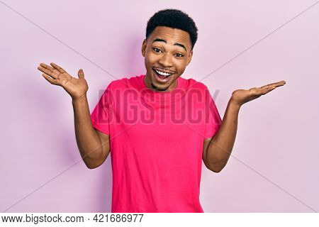 Young african american man wearing casua t shirt celebrating crazy and amazed for success with arms raised and open eyes screaming excited. winner concept 